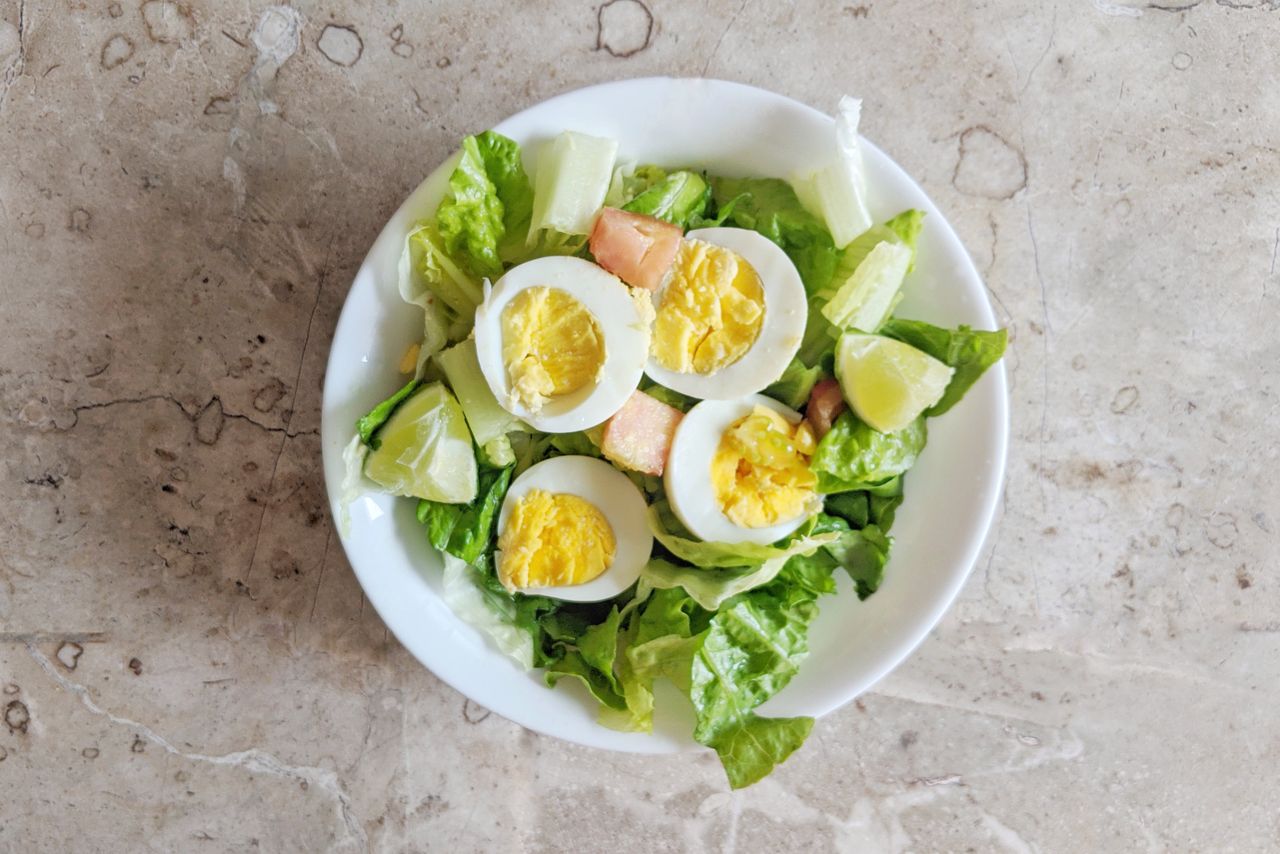 A fresh and nutritious salad featuring boiled eggs, lettuce, and vegetables on a ceramic plate.
